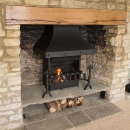 A re-modelled Cotswold fireplace with raised hearth including log store. Thermovent high performance wood burning open fire with stel canopy, hand