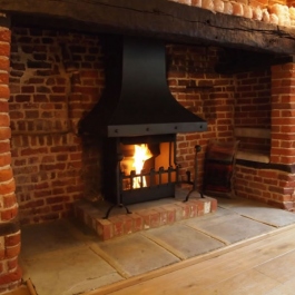 Anniversary Edition Thermovent high performance open fire installed in this large Inglenook open fireplace. The raised brick plint already in place.