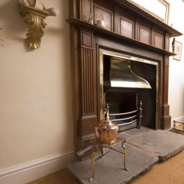 Antique stripped wood surround open fireplace with Georgian brass style canopy on Thermovent high performance convecting fire matches brass