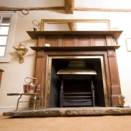 Classic stripped wood surround open fireplace with Georgian brass style canopy on Thermovent high performance convecting fire matches brass