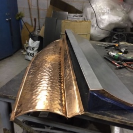 Hand beated and folded copper sheets ready to lay over the steel canopy on this long narrow canopy for an open fireplace