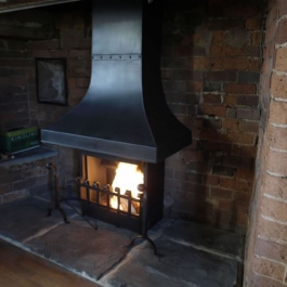 Large Inglenook fireplace with high performance Thermovent convecting open fire. Scroll top dog irons with swan neck ball top dog irons. Wood burning.