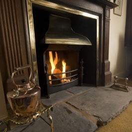 Natural wood surround open fireplace with Georgian brass style canopy on Thermovent high performance convecting open fire to match brass inner frame on the surround.