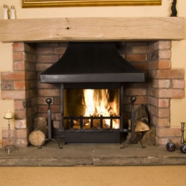 Open fireplace in new extension with steel canopy, hand forged grate front and dog irons. Conevecting open fire with built in flue baffle control.