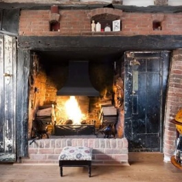 Preserved open fire with traditional canopy and bespoke grate used where chimney lined with large diameter liner. Storing logs this close not recommended.