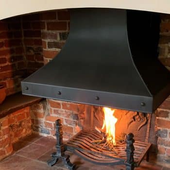 Large inglenook studded and riveted canopy with traditional fire grate