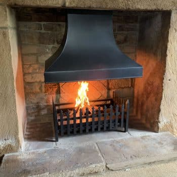 Steel inglenook canopy and hand forged spear fire basket.