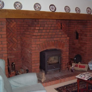 Small wood burning stone in open fireplace.